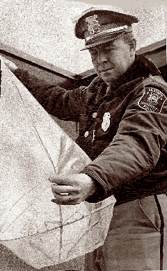 John E. Hayes, chef de la police de l'Université du Michigan de l'Est, examine un faux ovni de Yipsilanti composé d'un sac en plastique, d'une croix en plastique et de quelques chandelles